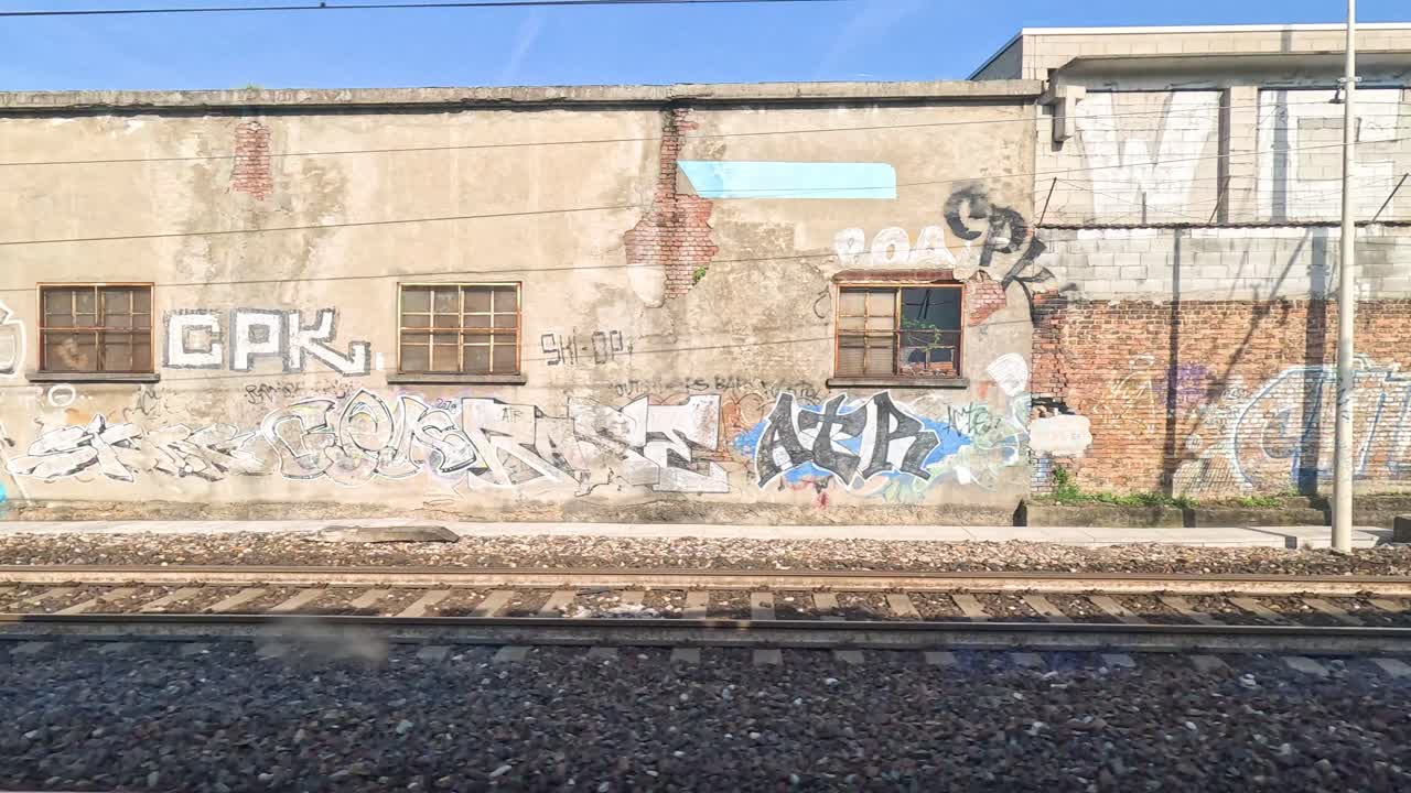 paredes cubiertas de graffiti vistas desde un tren en movimiento
