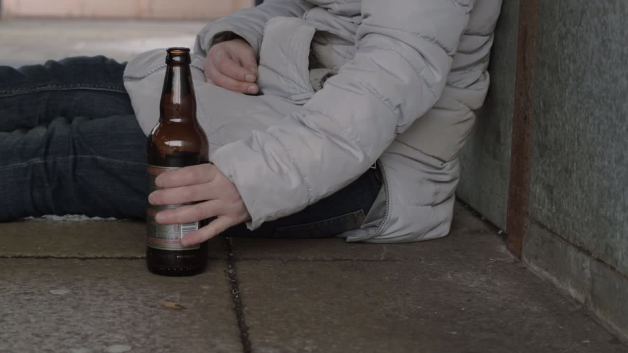 Woman sitting in urban scene drinking beer from bottle