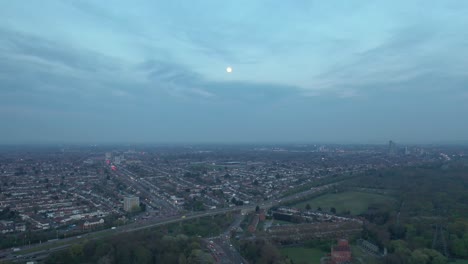 Redbridge-roundabout-and-A12-full-of-traffic-at-dusk,-Ilford-and-moon-in-background