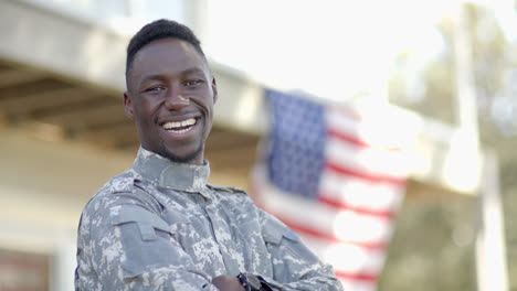 Happy-african-american-male-soldier-laughing-with-flag-in-background-on-sunny-day,-slow-motion