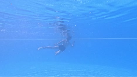in the tranquil embrace of a shimmering pool, a swimmer glides effortlessly below the surface, exploring the calm and vibrant underwater world around them