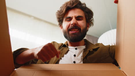 Happy-arabian-man-shopper-unpacking-cardboard-box-delivery-parcel-online-shopping-purchase-at-home