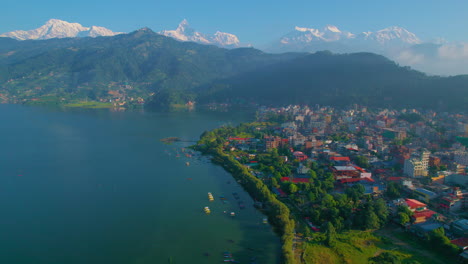 Drone-captures-a-breathtaking-view-of-Pokhara-city-as-it-glides-left,-revealing-the-pristine-Phewa-Lake,-bustling-Lakeside,-and-the-majestic-Macchapuchhre-and-Annapurna-mountain-range-in-the-distance