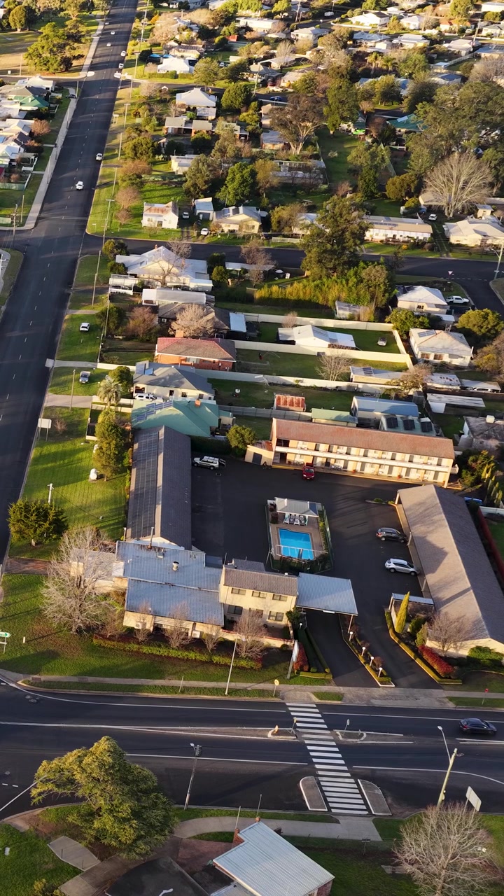 Ripresa aerea con drone dall'alto di case residenziali, strade e un motel a Coonabarabran, Australia.