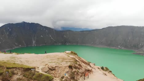 aerial push in dolly shot with scenic viewpoint overlooking the turquoise quilotoa lake in ecuador