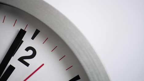 close up of a white ticking clock on white background, pointing one minute to midnight
