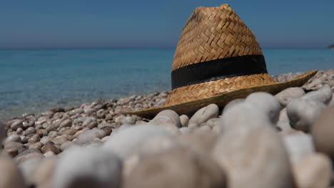 Nahaufnahme-Von-Strohhut-Am-Kiesstrand-Mit-Verschwommenem-Hintergrund-Des-Mittelmeers