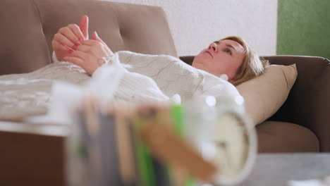 emotional healer lying on sofa in contemplative room conversing softly while hands clasped near chest blurred clock and pencils on desk foreground creating therapeutic atmosphere peacefully