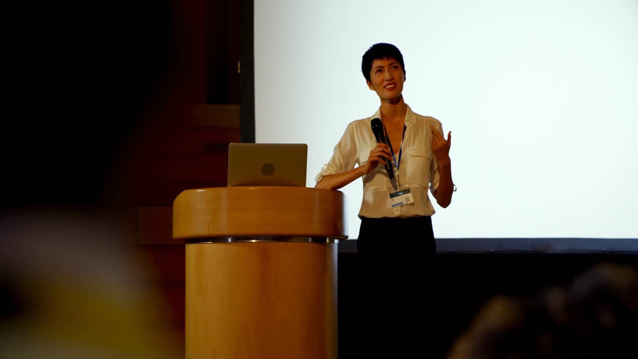 Giovane donna d'affari asiatica che parla a un seminario aziendale in un auditorium 4k