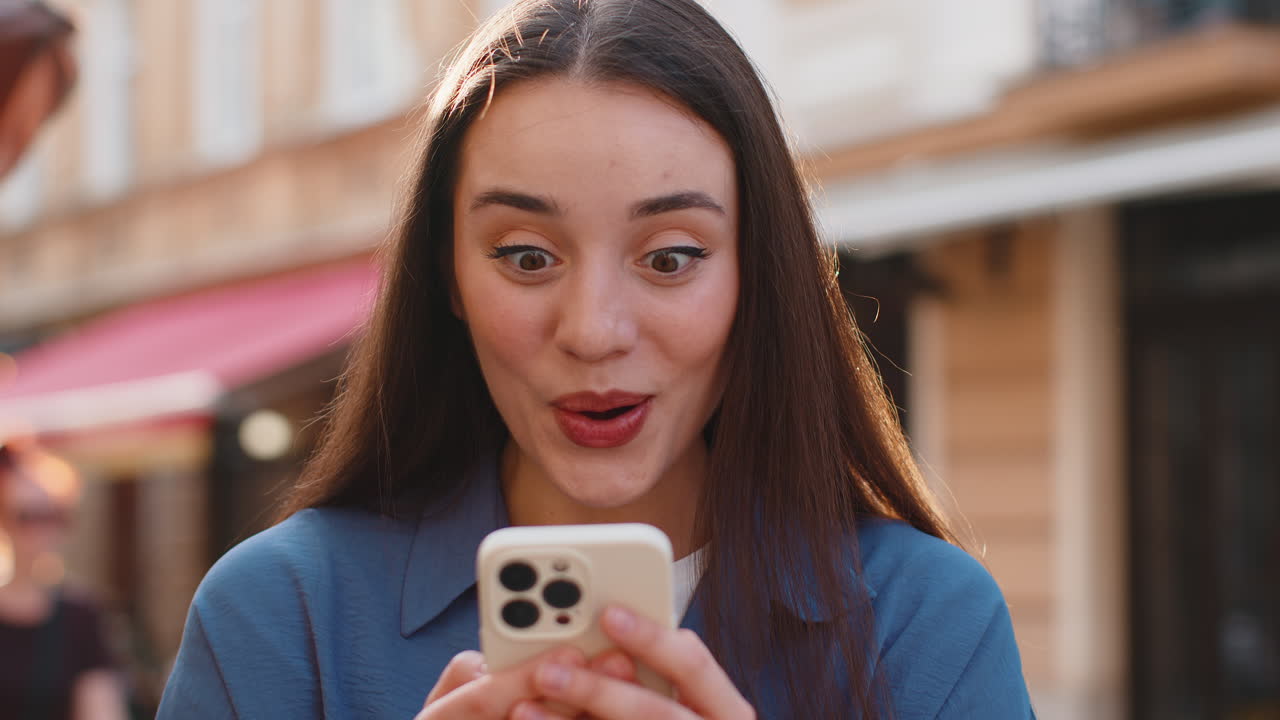 Forbløffet kvinde bruger smartphone fejrer vinde gode beskeder nyheder lotteri jackpot sejr i byens gade