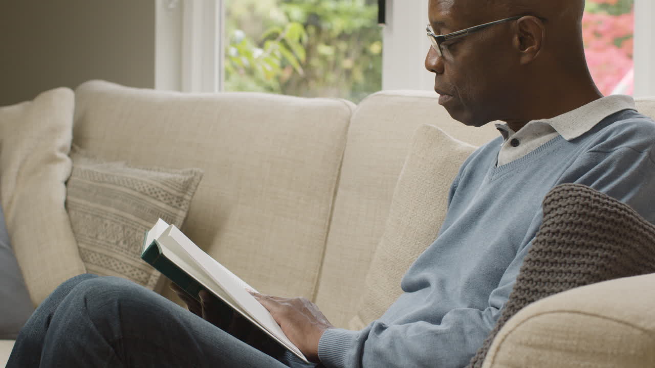 Middle Aged Man Sitting In His Living Room Reading a Book