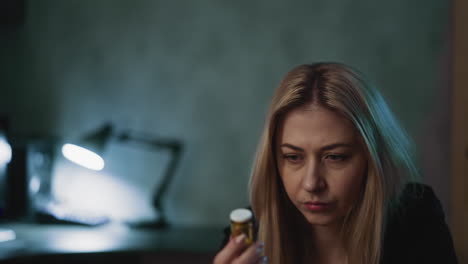 Depressed-woman-looks-at-pill-bottle-thinking-about-suicide