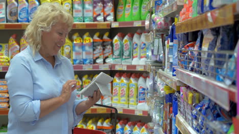 mujer que usa un bloc de papel comprando productos químicos para el hogar en la tienda
