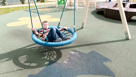 happy boy is swinging on empty webbed swing.