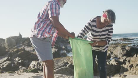 senior african american couple cleaning beach, slow motion