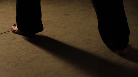 barefoot woman dancing flamenco with black trousers on a floor doing exercise dance tango or judo karate steps