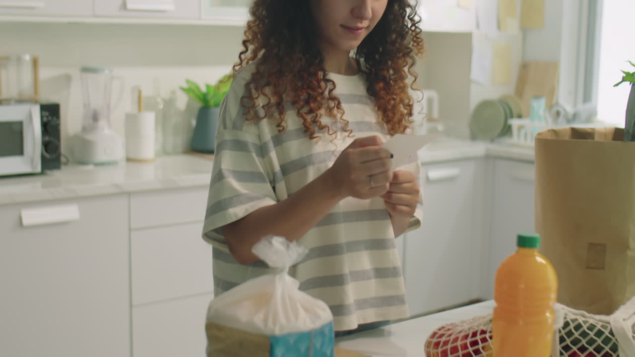 Girl Reading Receipt from Supermarket at Home