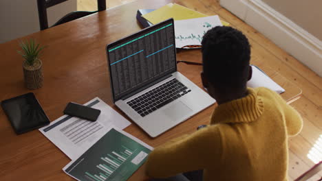 hombre afroamericano sentado en el escritorio codificando datos en una computadora portátil