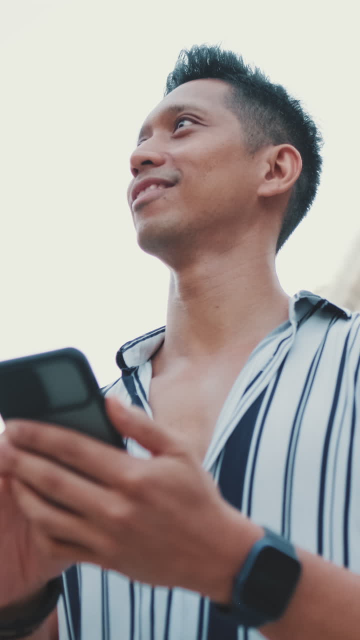 Man holding a cell phone looking up at a building