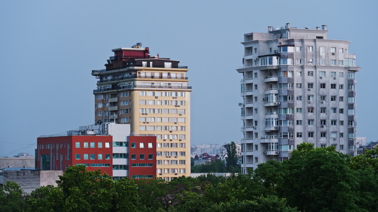 Tall buildings surrounded by green trees with the sky on the background in Chisinau, Moldova in the evening