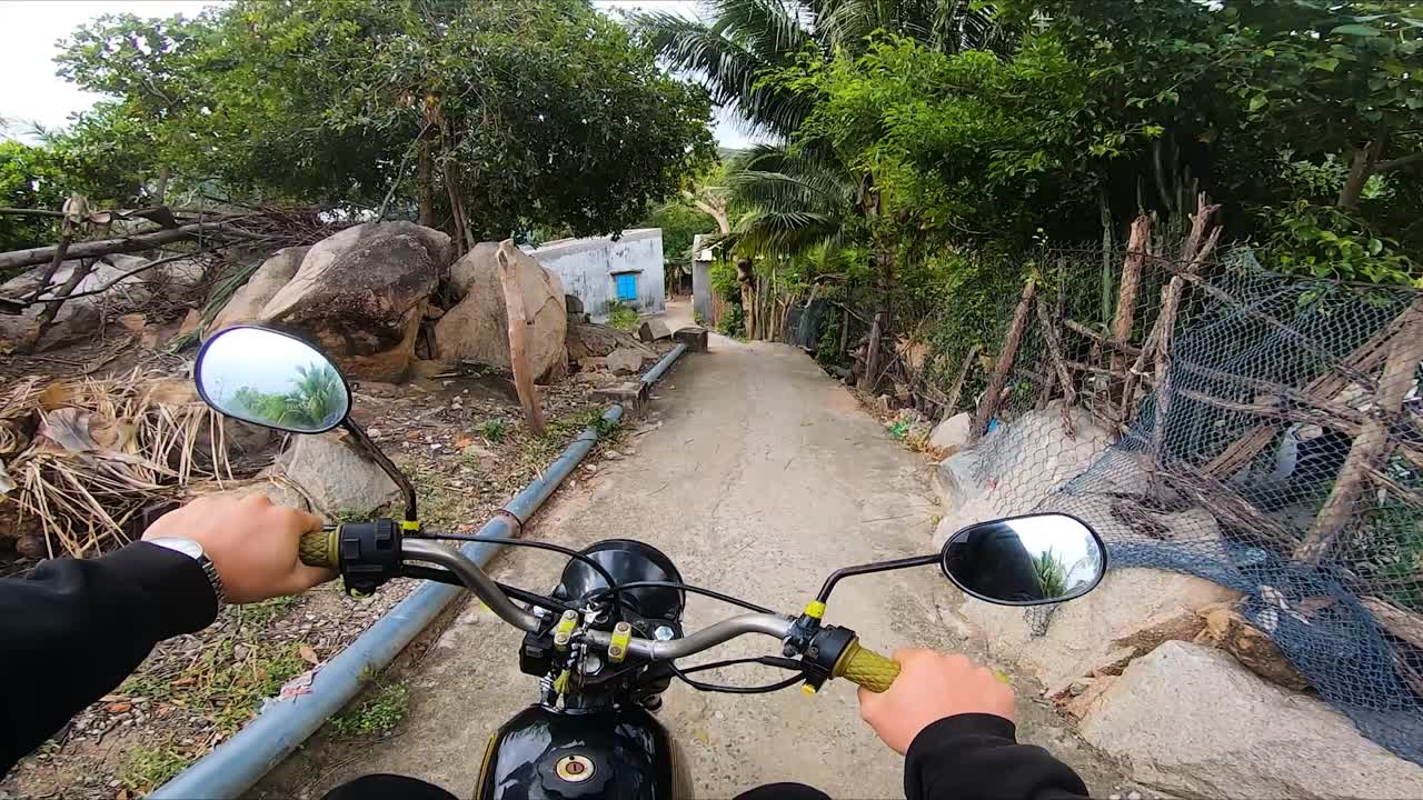 toma en primera persona de un hombre conduciendo una motocicleta por un sendero estrecho en una zona de viviendas local de vietnam