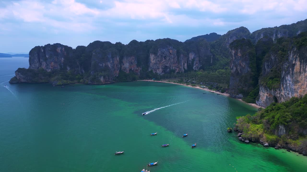 Railay Beach, showcasing its famous limestone cliffs, lush greenery, and the vibrant turquoise waters of the Andaman Sea. Perfect aerial view flight panorama overview drone