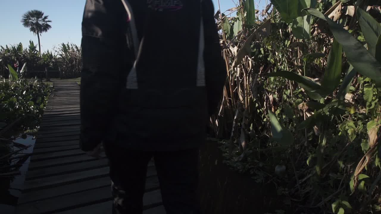slomo vista trasera de una mujer caminando sobre una plataforma de madera en laguna blanca