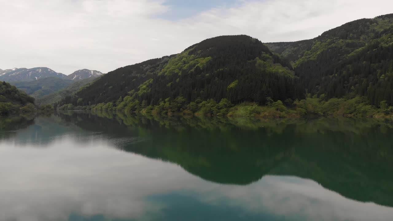 Aerial Drone fly Mountain Lake Surrounded by Verdant Forests, in Gifu Japan, Clear Skies