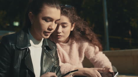 jóvenes amigas hablando y usando un teléfono al aire libre