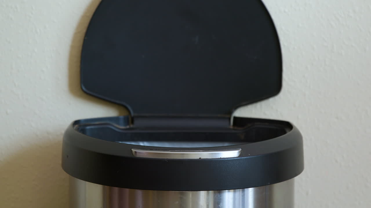 Man Throws Away Yellow Package in Motion Sensing Touchless Trash Can - Close-Up
