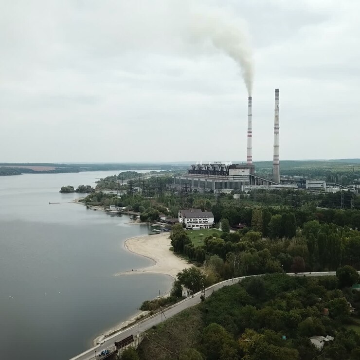 Aerial view of coal power station with smoke goes from tubes. Fog or clouds cover the land. View from the birds-eye view.