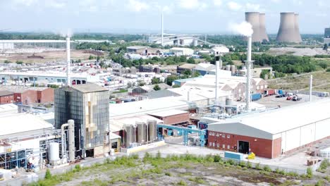 Industrial-warehouse-power-plant-refinery-buildings-under-smokestack-wasteland-aerial-view-dolly-right-forwards