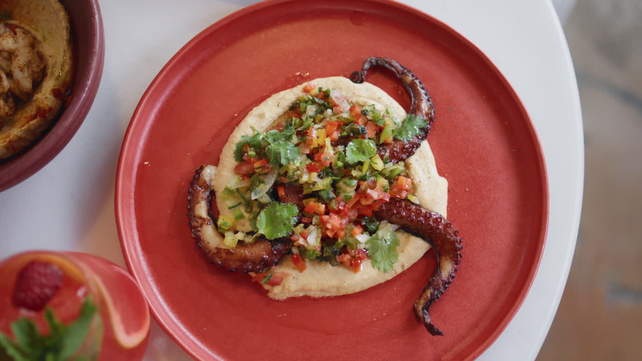 tentáculos de pulpo de primer plano plato de hummus con hierbas y verduras en el restaurante