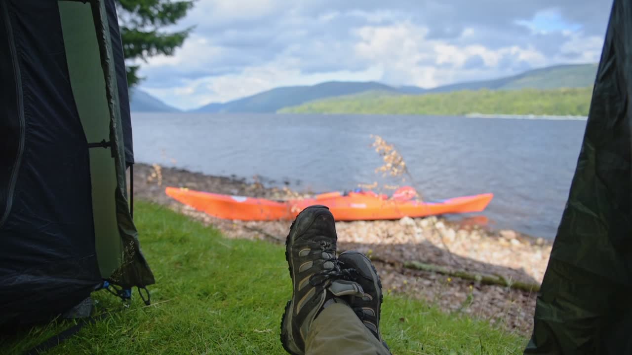 Feet On A Relax Position In A Tent With A Small Orange Kayak In Caledonian Canal. -medium shot