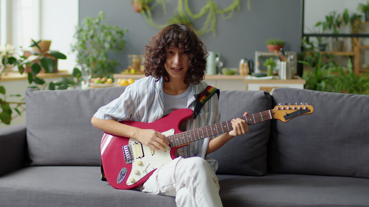Female Music Blogger Playing Guitar and Speaking on Camera