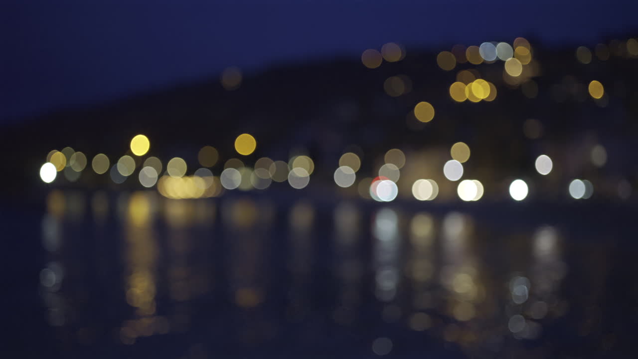 Blurred view of city lights reflecting on the sea in the evening