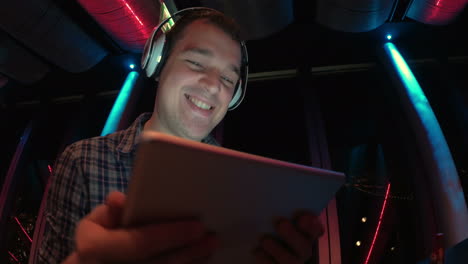 Man-enjoying-music-with-pad-at-sky-deck-at-night