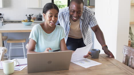 a young african american couple is focused on finances using a laptop