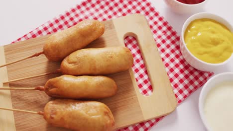 video of corn dogs with dips on a white surface