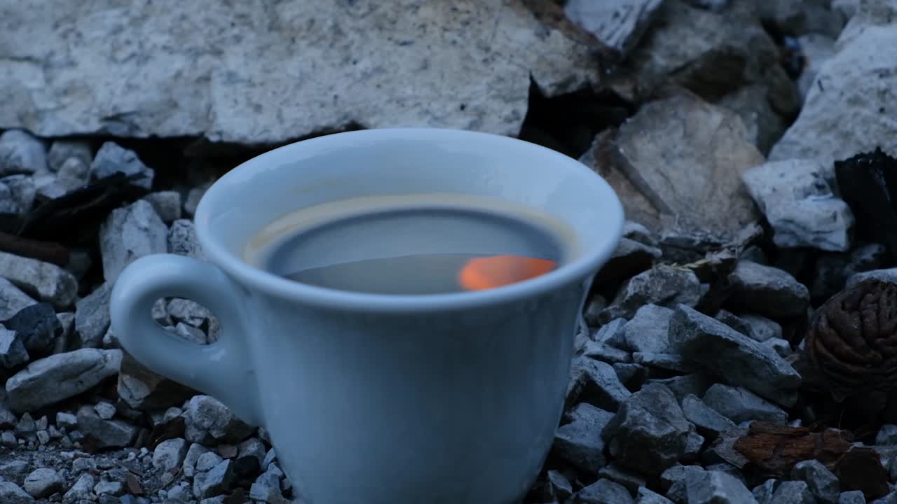 Bonfire reflecting off instant coffee cup in slow motion