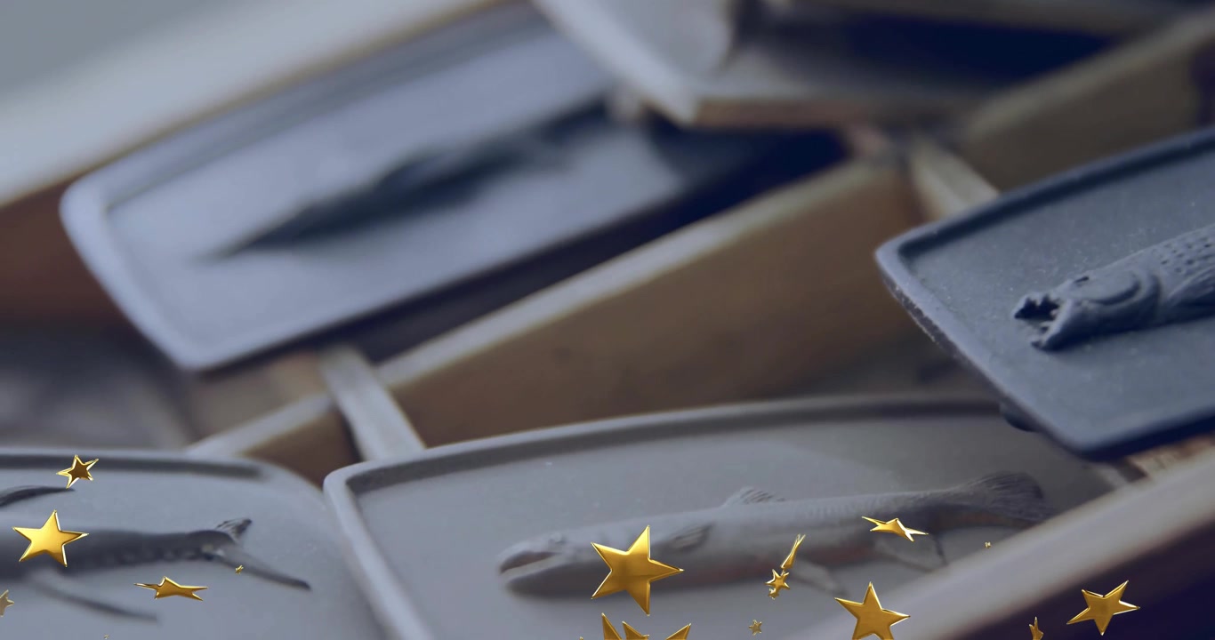 Golden star confetti appearing at bottom drifting upward over stacked trays displaying elegance