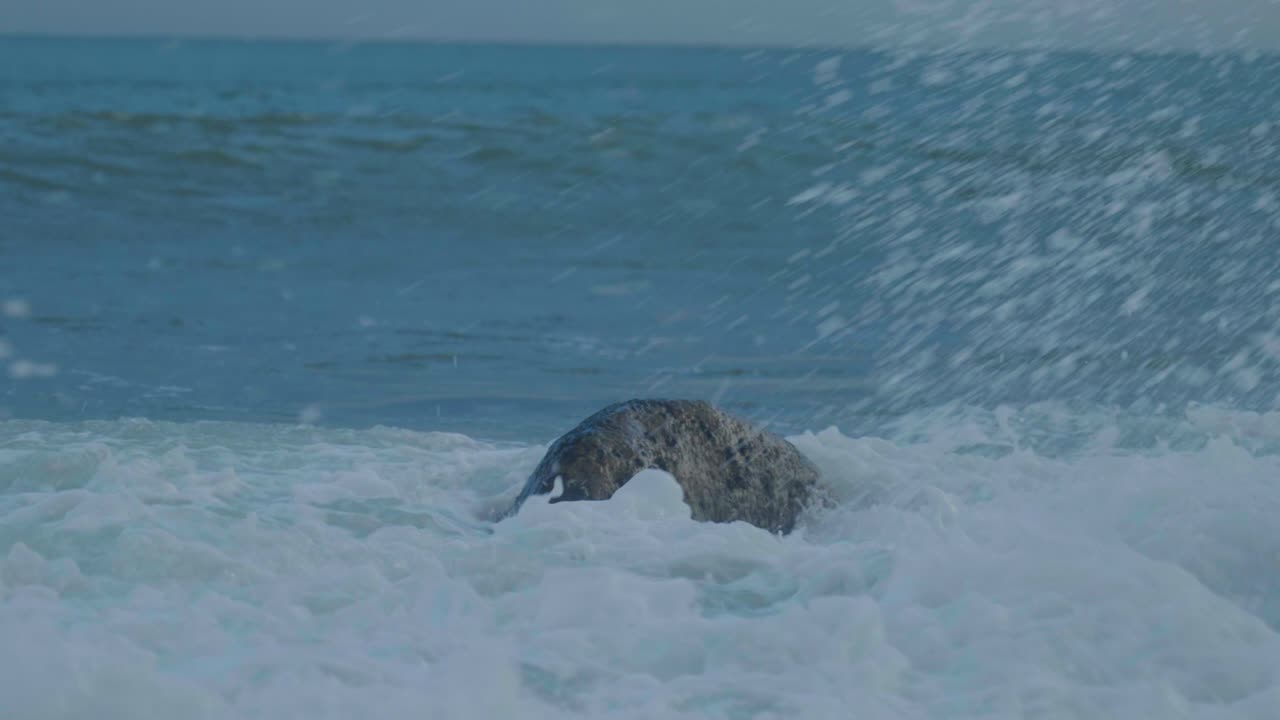 4K Cinematic slow motion shot of waves hitting rocks on the beach during sunset, at Church Ope, on Portland, Dorset.