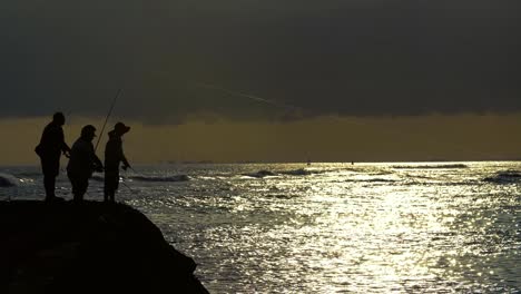 three fishermen cast during sunset at ala moana beach park in honolulu hawaii