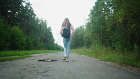 teenage student walking alone along quiet rural road surrounded by lush green trees, carrying backpack, dressed in hoodie and jeans, heading to school on peaceful morning under cloudy sky
