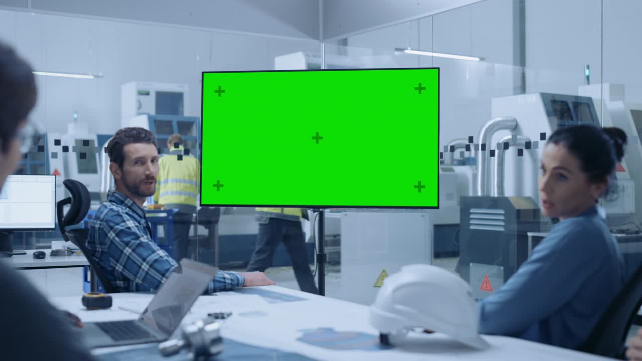 현대적인 공장 사무실 회의실: 다양한 엔지니어 팀, 관리자 및 투자자가 회의 테이블에서 이야기하고, 녹색 화면 크로마 키 모형을 보여주는 인터랙티브 tv를보고 있습니다.