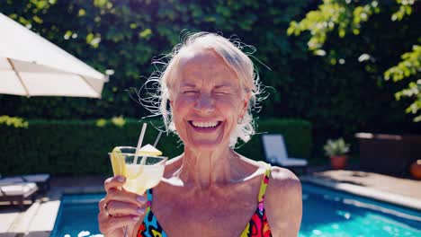 senior woman enjoying a cocktail by the pool