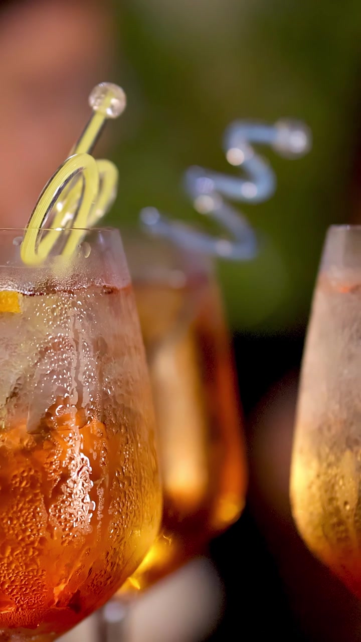 Una guarnizione di scorza di limone si avvolge rapidamente in un cocktail Negroni ghiacciato, primo piano, illuminazione ambientale calda