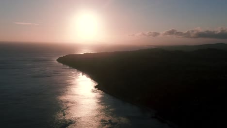 aerial dolly shot of early sunrise with tropical green island in foreground
