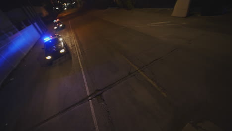 fpv drone shot of two police cars responding with flashing lights at night