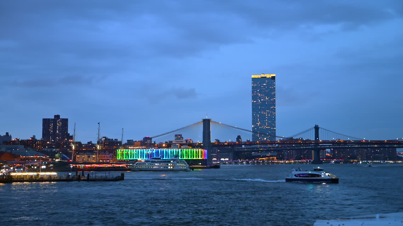 Brooklyn Bridge with Manhattan in the background. The Brooklyn Bridge extends over the East River with Manhattan skyline visible behind it at nightfall